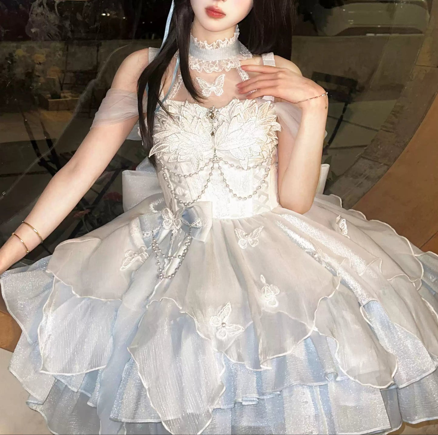 Person wearing a white lace dress with a decorative headpiece indoors.