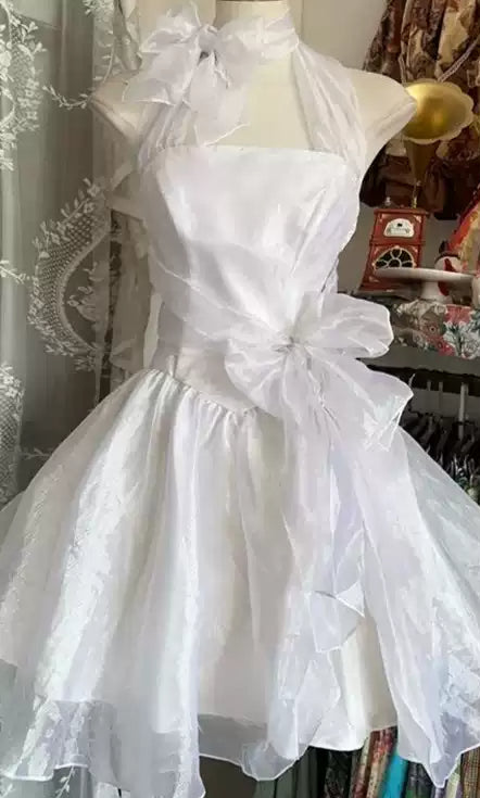 White dress with large bows on a mannequin, displayed by Natural Studio.