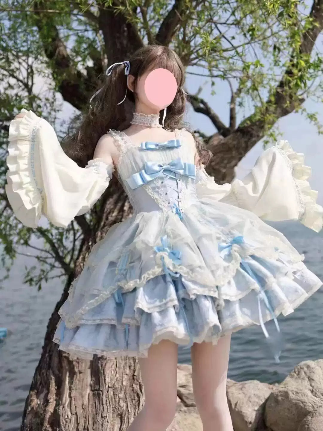 Person wearing a light blue and white dress with ruffles by a tree