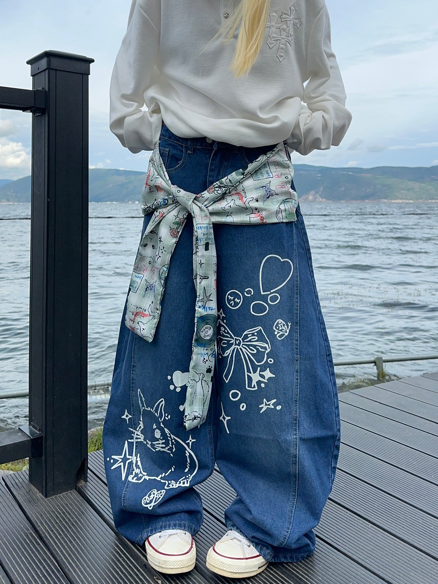 Graffiti strap-detailed curved wide-leg jeans.