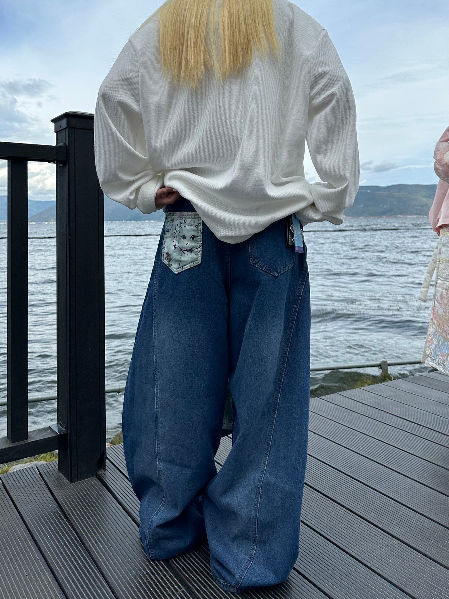 Graffiti strap-detailed curved wide-leg jeans.