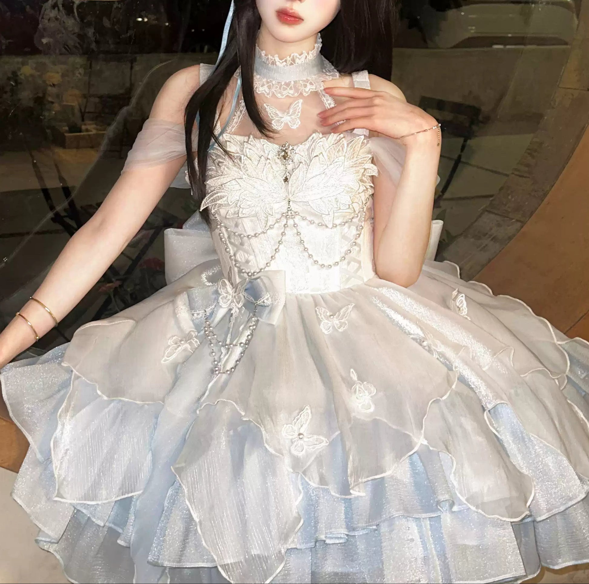 Person wearing a white lace dress with a decorative headpiece indoors.